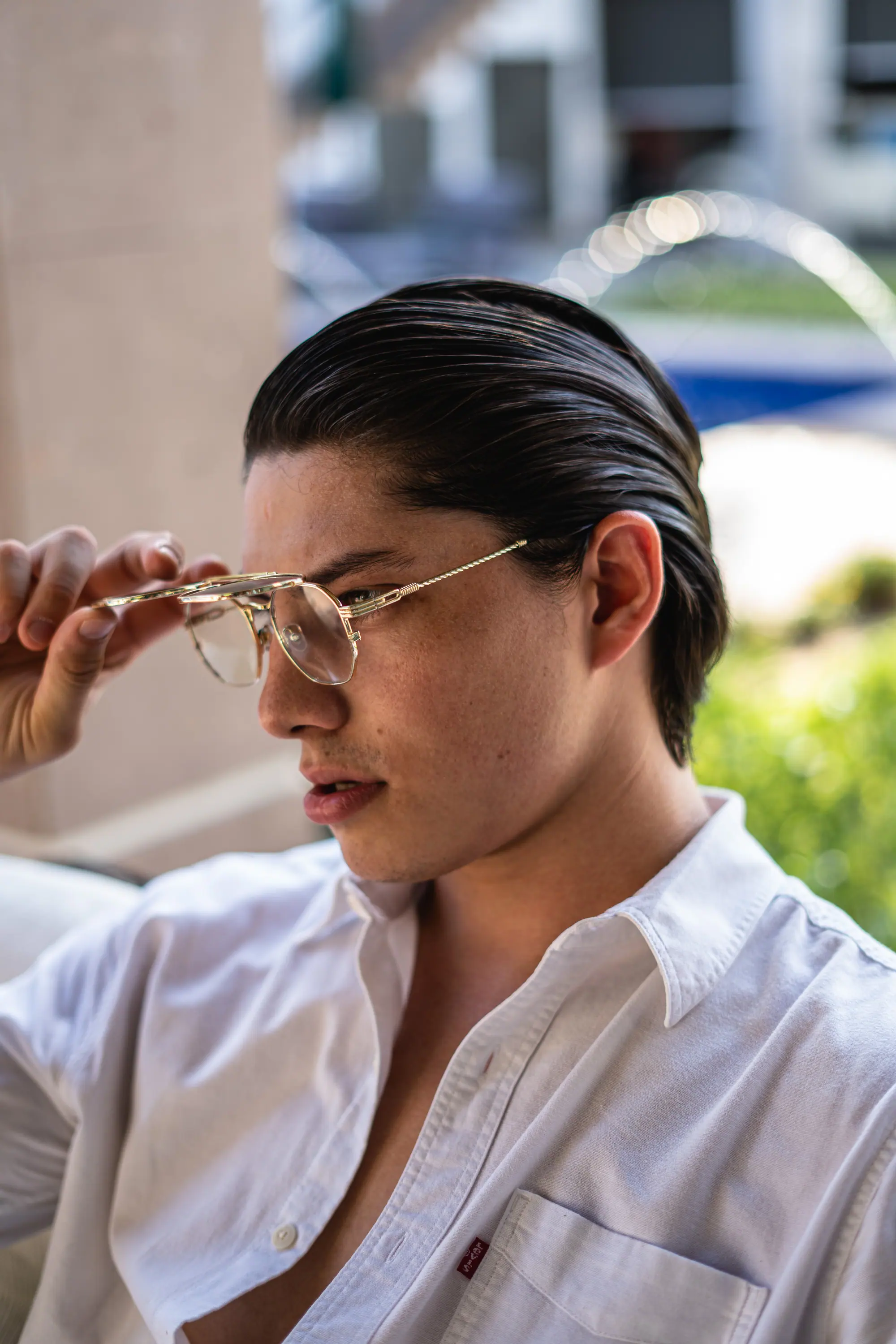 Modelo bajándose unos lentes dorados junto a la fuente