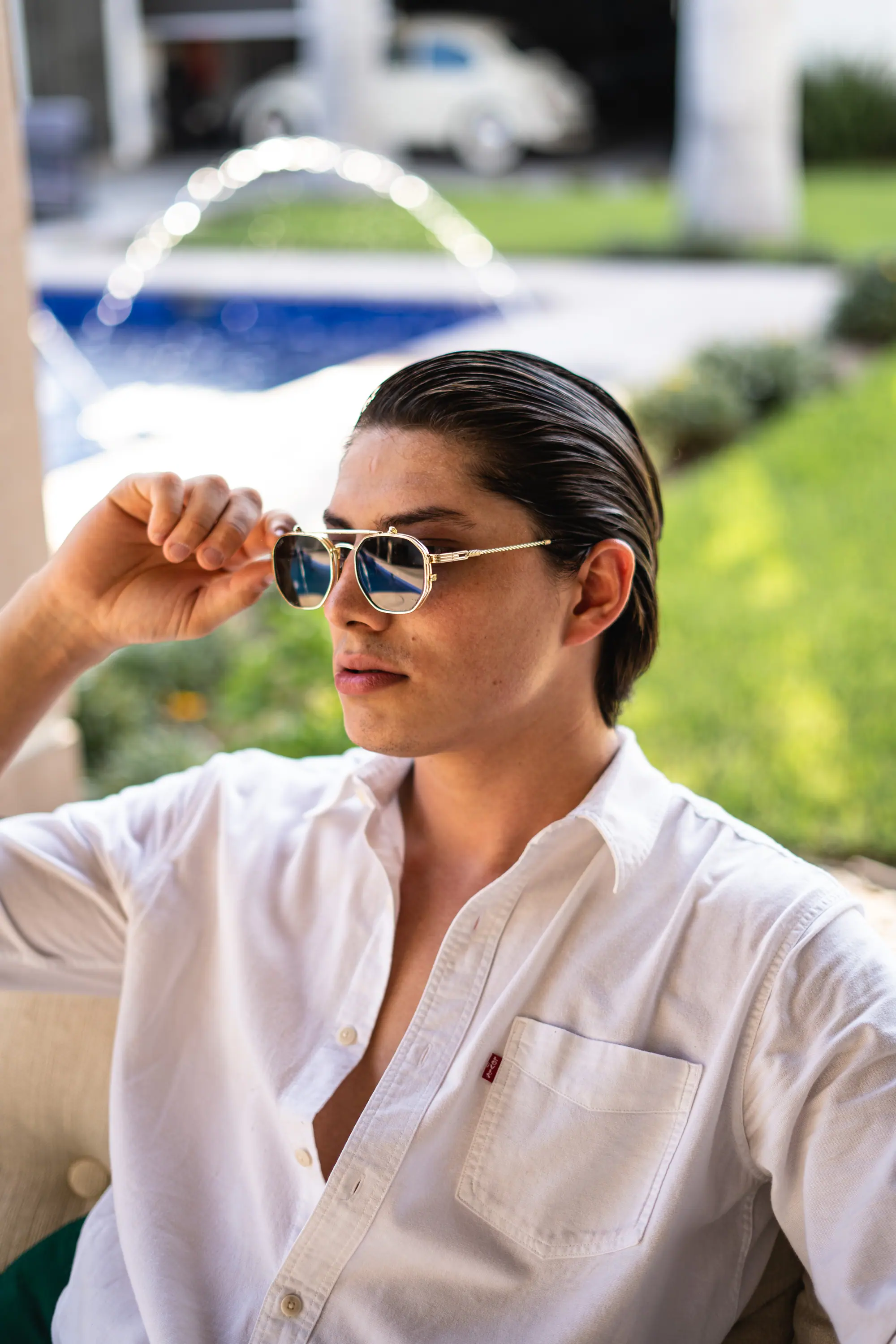 Camisa blanca y lentes de aviador frente a la alberca